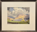 Framed artwork of a landscape with mountains and a lake.